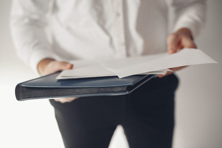 Handsome man in a white shirt. Businessman working in a office. Guy with a folder with documents.